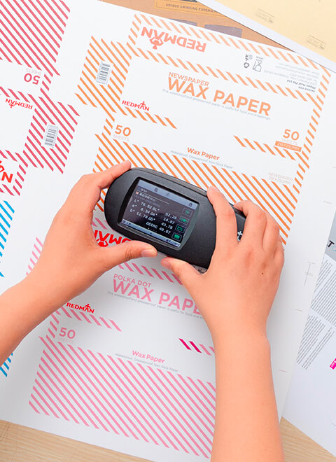 checking color of a wax paper packaging box with X rite color monitoring instrument