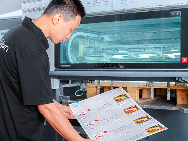 a machine master is checking the packaging boxes' output quality in front of the Heidelberg printing machine